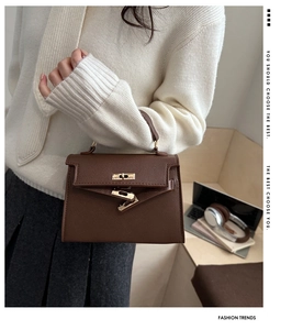 Detailed view of dark brown textured leather handbag with gold metal hardware on office desk