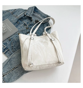 Detail of white pleated tote bag with silver hardware and adjustable shoulder strap