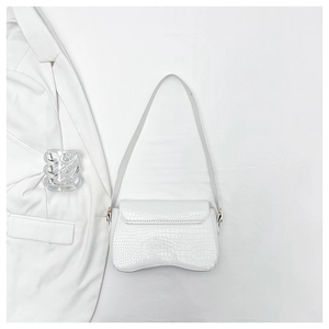 Detail of white crocodile pattern shoulder bag with curved bottom and golden hardware