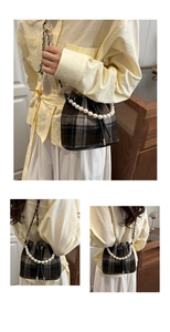 Detail view of plaid bucket bag with pearl handle and metal chain strap in soft lighting