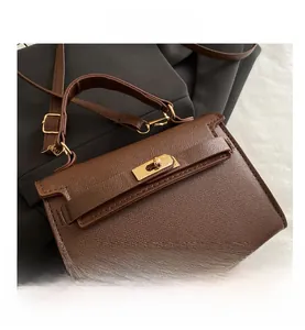 Detail of brown litchi leather bag showing gold turn-lock closure and sturdy top handle