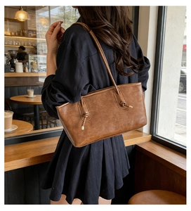 Detailed view of brown leather tote bag with elegant knot straps and brand embossing