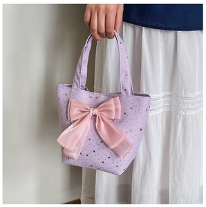 Detail of lavender star print tote bag with a glossy pink bow and soft fabric texture