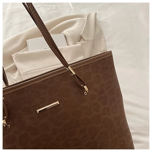 Details von Leopardenmuster-Wildlederstruktur und Goldbeschlägen an brauner Tasche
