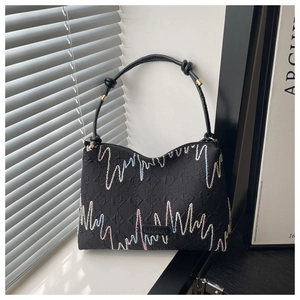 Detail of black canvas tote featuring lettered jacquard and colorful wave stitching