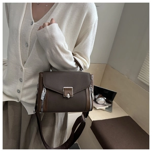 Detail view of coffee PU leather bag with silver snap button and woven shoulder strap