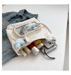 Vue de dessus du cabas blanc avec poche transparente, peluche étoile et objets du quotidien
