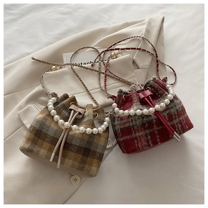 Detail of plaid bucket bag featuring a pearl handle and chain shoulder strap