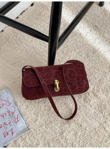 Detail of burgundy leopard print shoulder bag with gold twist lock on plush carpet