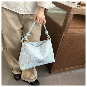 Close-up of light blue canvas tote with FF embossed pattern and wavy embroidery detail