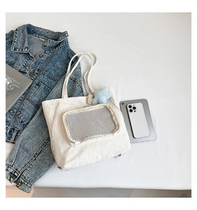Détail d'un sac cabas en toile blanche avec poche filet zippée et breloque étoile bleue
