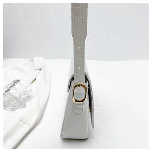 Detail of white crocodile pattern shoulder bag featuring golden metallic buckle hardware