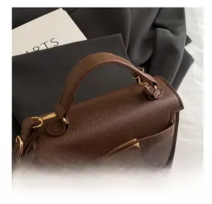 Detail of vintage brown lychee grain leather bag with gold twist lock and handle