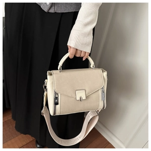 Close-up of beige canvas and cream leather handbag with decorative zippers and fashion strap
