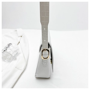 Detail of white crocodile pattern shoulder bag featuring golden square buckle and side strap