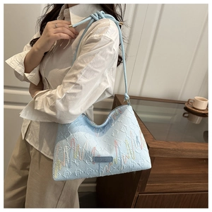 Detail of light blue faux leather shoulder bag with F-pattern embossing and wavy stitching