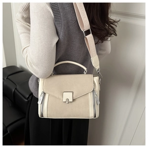 Detail of cream crossbody bag featuring metal buckle and textured wide fabric strap