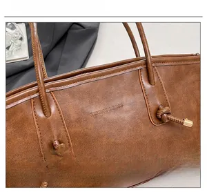 Detail of vintage brown leather tote bag with embossed fashion text and gold metal accents