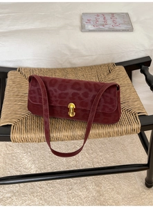 Close-up of vintage burgundy leopard print suede baguette bag with gold metal buckle
