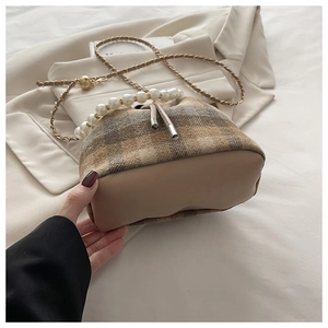 Detail of checkered bucket bag featuring oversized pearl handle and metallic chain strap