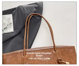 Detail of comfortable thin round shoulder straps on the brown leather tote bag with gold metal tips