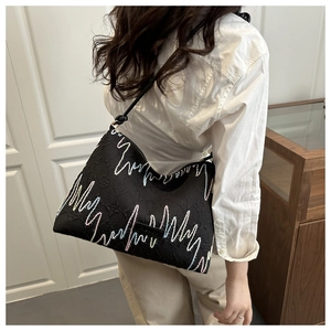 Detail of black striped bucket bag with colorful zigzag stitching and a knotted strap