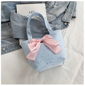 Detail of light blue tote bag featuring pink silk bow and silver star patterns
