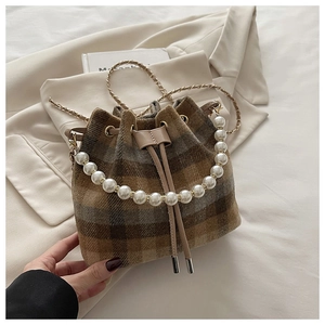 Close-up of wool bucket bag with plaid pattern, pearl handle, and drawstring closure