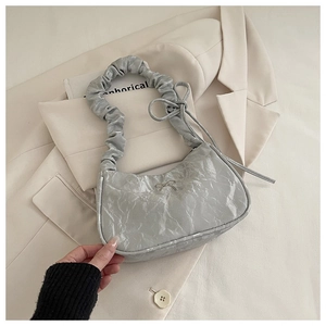 Detailed view of silver metallic pleated shoulder bag with delicate bow and cloud strap