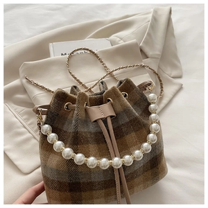 Detail of checkered bucket bag featuring pearl handle and metallic chain strap