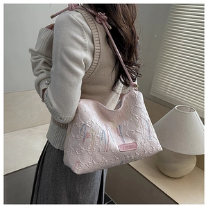 Close-up of pink quilted tote bag featuring colorful letter embroidery and fashion label