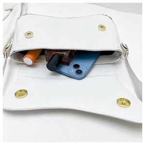 Detail showing white crocodile texture handbag interior with phone and cosmetics