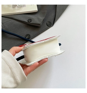 Détail d'un mini sac bandoulière avec corps blanc et rabat rouge en cuir mat élégant