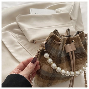 Detail of tweed bucket bag with elegant pearl handle and leather chain shoulder strap