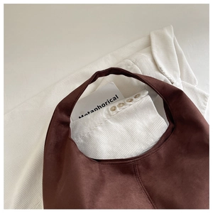 Detail of dark brown suede hobo bag texture and stitching on white corduroy background