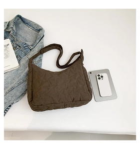 Detail of dark brown star-quilted shoulder bag with adjustable wide strap and nylon finish