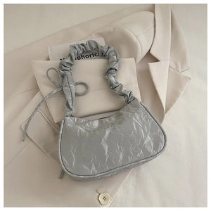 Close-up of silver pleated handbag featuring cloud handle and side bow knot detail