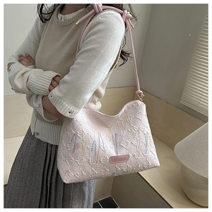 Close-up of pink embossed leather tote featuring colorful embroidery and knot shoulder strap