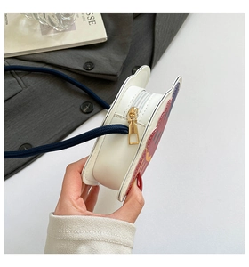 Détail de sac bandoulière en cuir PU blanc avec sangle tressée et zip doré