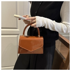 Detail of caramel patent leather bag with a triangular flap and shiny mirror finish
