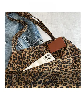 Close-up of leopard print canvas tote bag with front pocket and leather patch detail