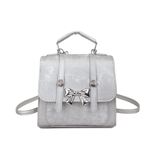 Silver-grey square tote bag with metallic bow detail and adjustable straps on white background