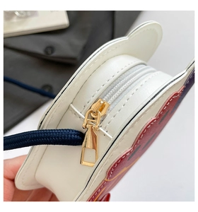 Détail d'un sac de dessin animé en cuir blanc montrant la fermeture éclair dorée