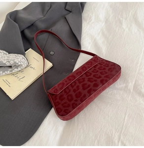 Detail of burgundy leopard print suede baguette bag styled with a grey blazer
