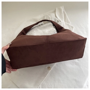 Macro shot of brown suede shoulder bag showing reinforced stitching and retro texture