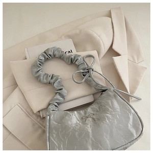 Close-up of silver butterfly handbag with metallic pleated texture on a blazer