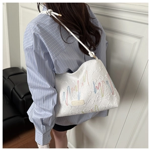 Detail of white bucket bag with rainbow embroidery and textured fashion label