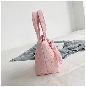 Detail of pink canvas tote bag featuring silver star patterns and a large silk bow accent