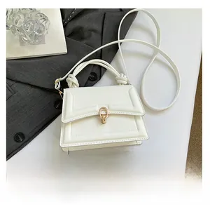 Dettaglio mini borsa bianca con chiusura a scatto dorata e manico a nodo unico