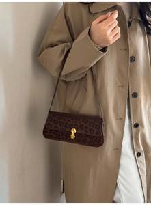 Macro detail of leopard print shoulder bag with gold metal twist lock and sleek leather strap
